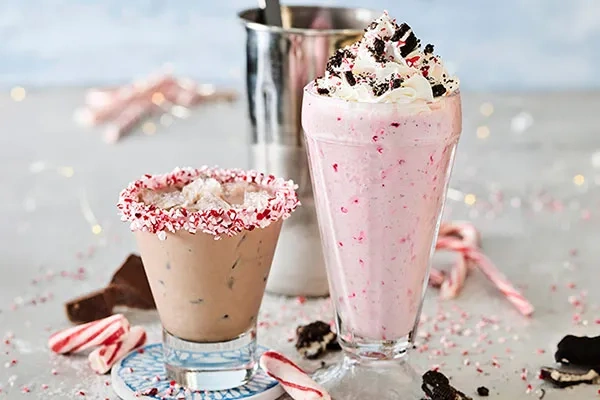 two holiday drinks with crushed candy canes